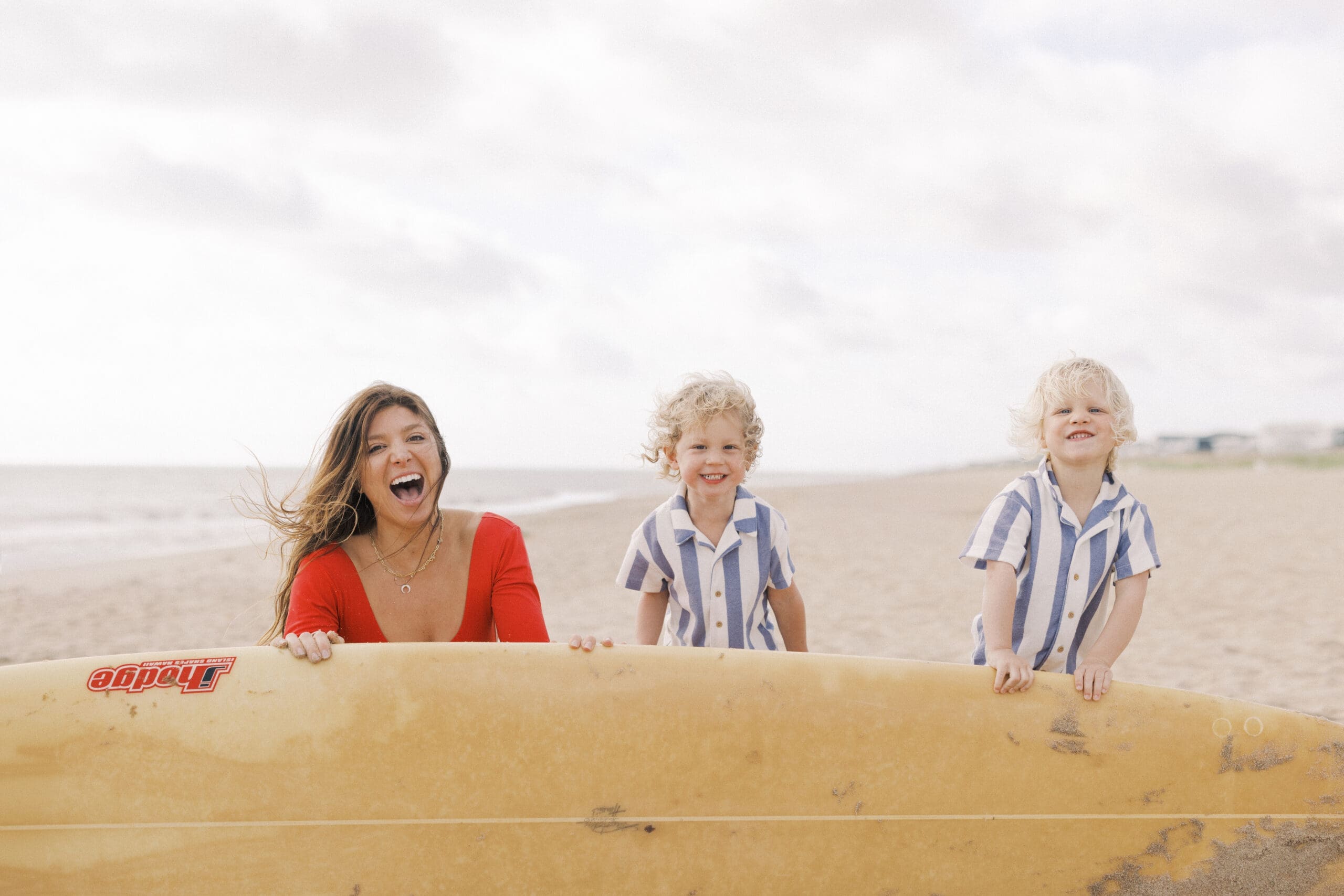 Mother playing with her twin toddler boys along the shoreline at Sandbridge Beach during a relaxed sunrise motherhood photography session in Virginia Beach.