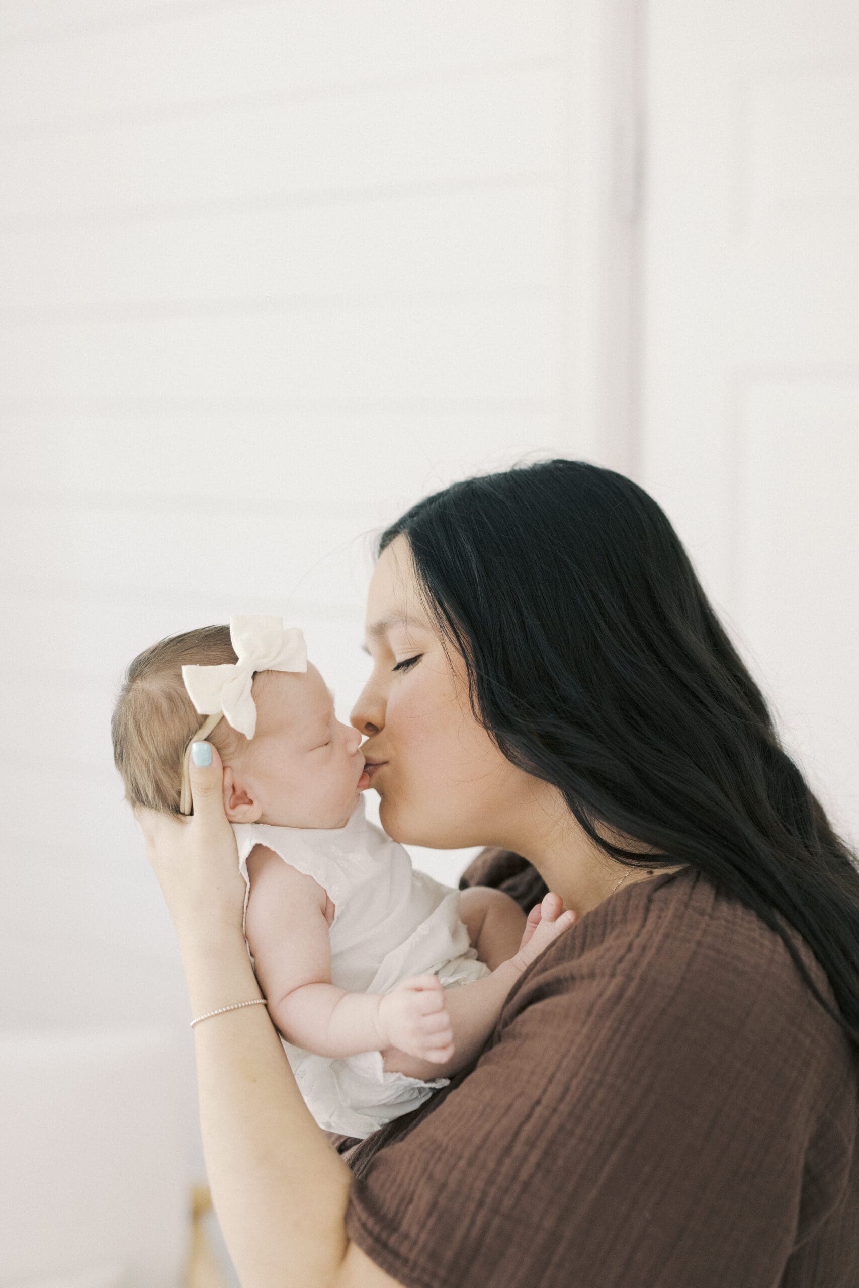Parents holding their newborn baby during a cozy in home newborn photography session in Hampton Roads with soft natural window light and neutral tones.